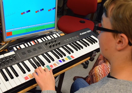 bilde viser et barn som spiller på keybord med farger
