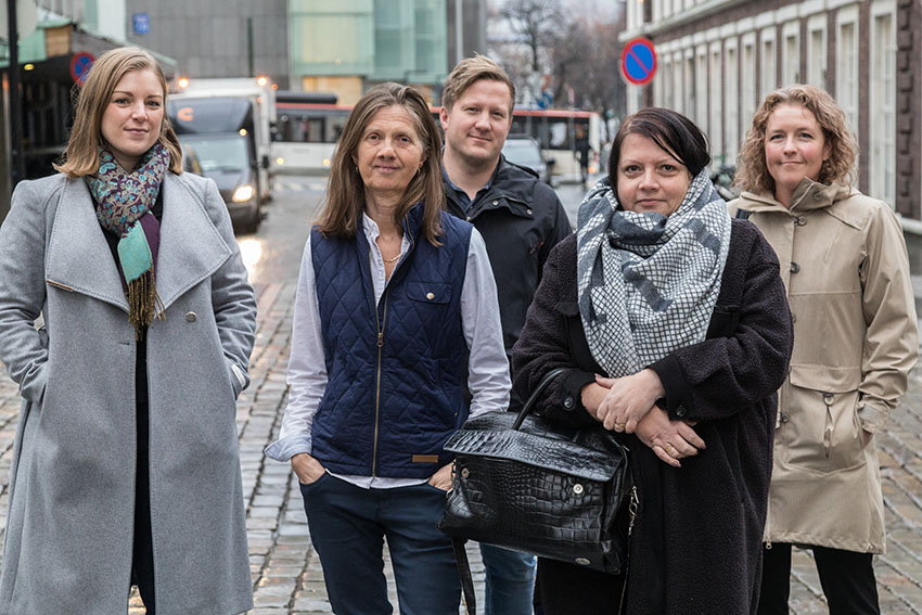 Bilde av fem mennesker som står utendørs. Alle smiler og ser mot kameraet