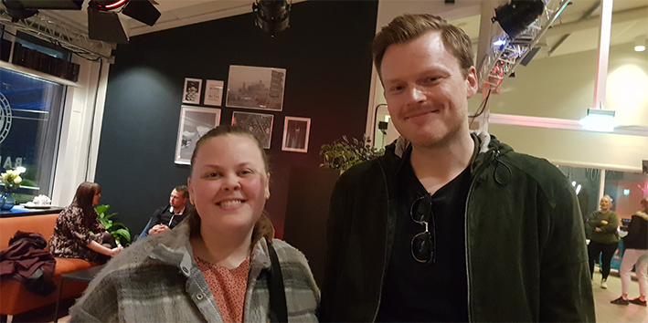 To personer ser i kameraet og smiler